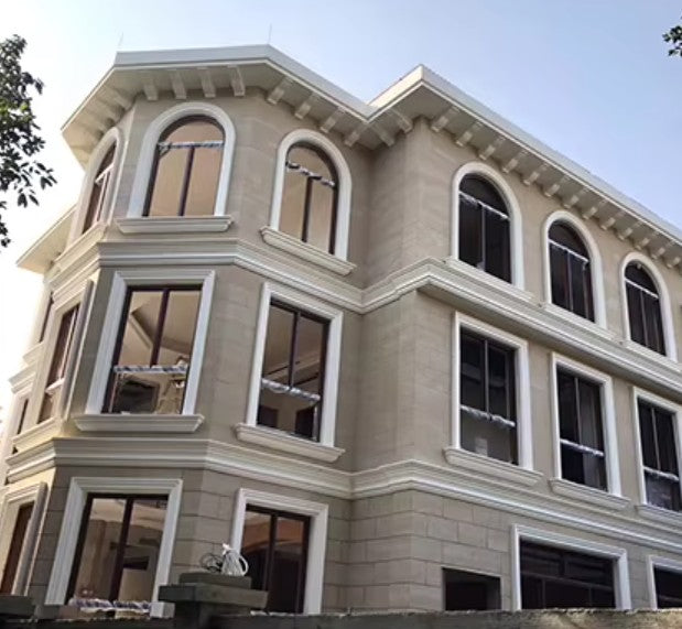 Three-story building ALL WALL WAS COVERED WITH 3D PR SLATE FLEXIBLE NATURAL STONE with arched windows and decorative cornices against a clear blue sky.